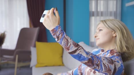 Happy-and-cool-young-woman-taking-photo-on-phone-at-home